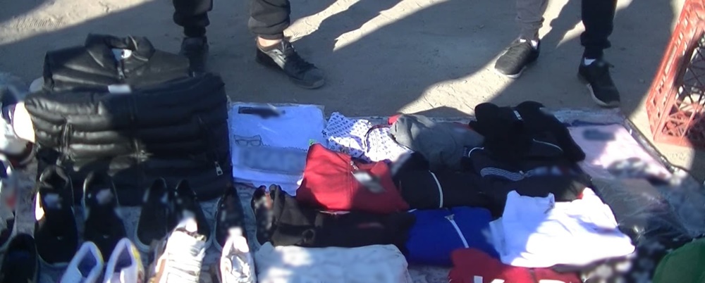 Haine și încălțăminte „de firmă”, la vânzare pe pătură, în oborul de&nbsp;animale